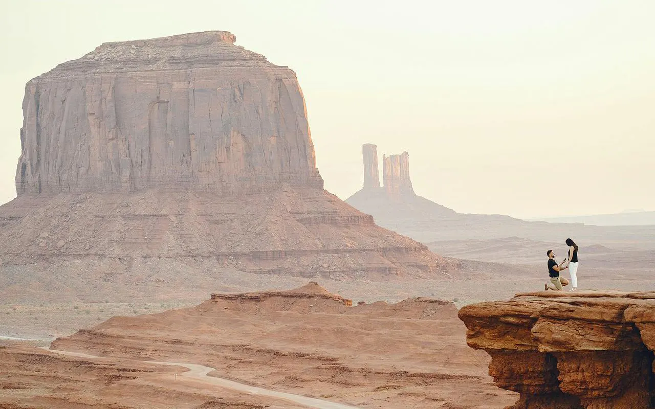 Couple on cliff with desert landscape, resembling Wadi Rum, during Amman to Petra tour.