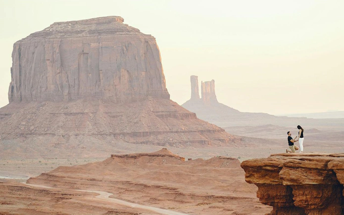 Couple on cliff with desert landscape, resembling Wadi Rum, during Amman to Petra tour.