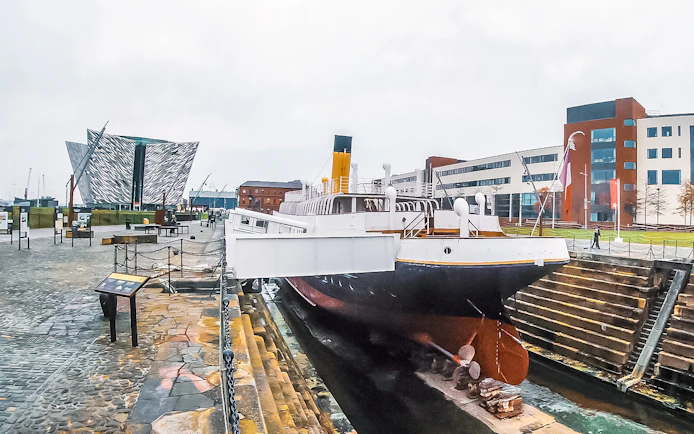 Titanic museum shipyard with historic ship and modern building in Belfast.