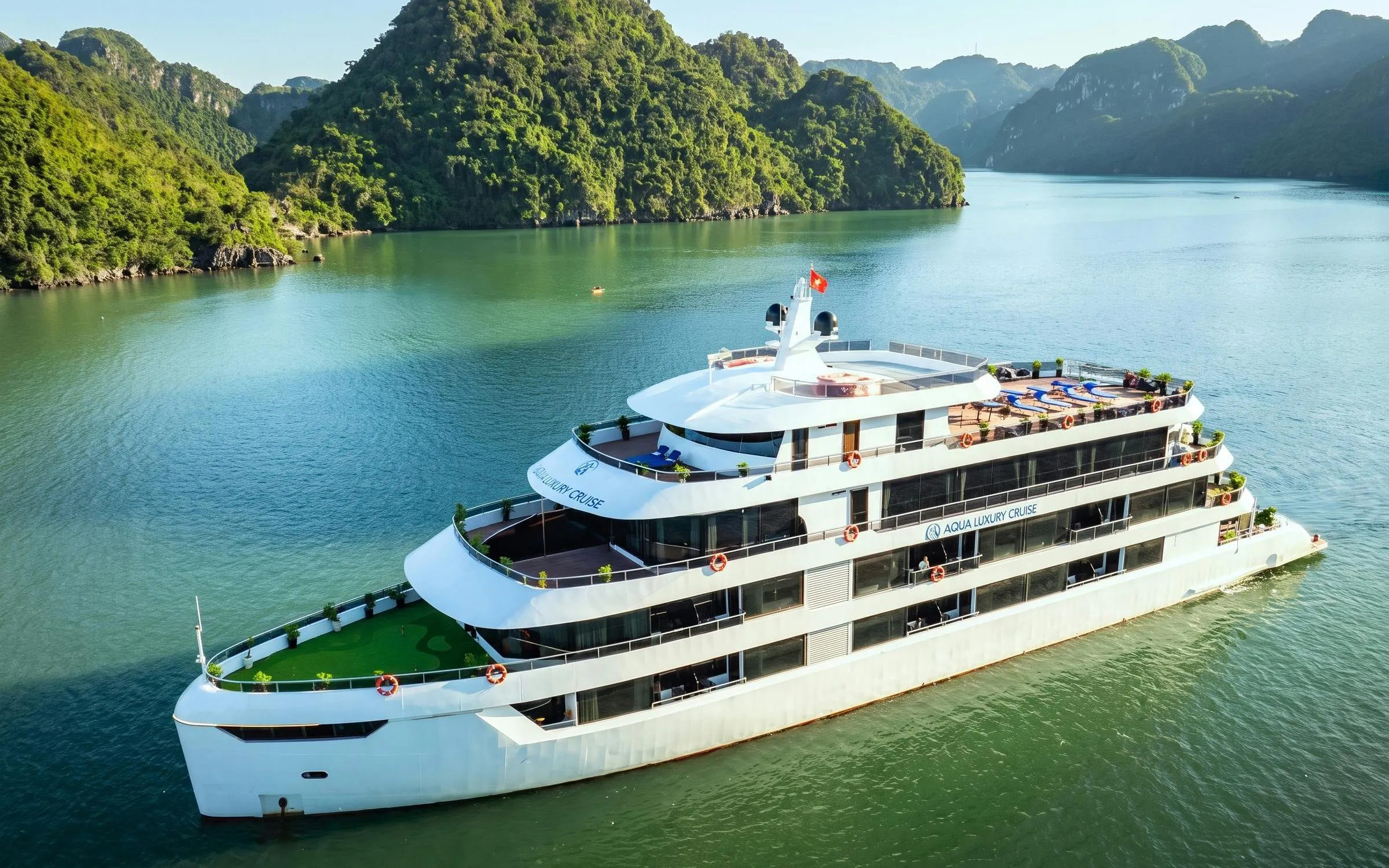 Luxury cruise ship sailing through Ha Long Bay with lush green islands in the background.