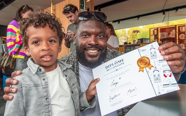 Child and adult holding a captain's diploma on a Seine family cruise in Paris.