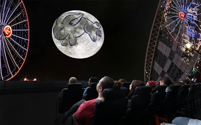 Visitors watching a moon projection with a rabbit drawing at a Chicago planetarium.