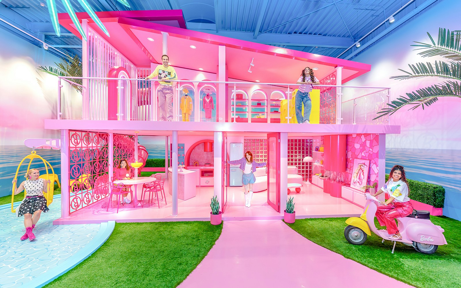 Barbie Dreamhouse experience with visitors exploring vibrant pink rooms and outdoor swing.