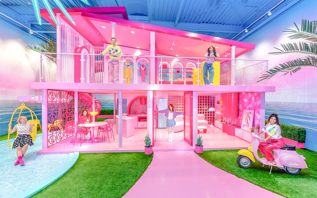 Barbie Dreamhouse experience with visitors exploring vibrant pink rooms and outdoor swing.