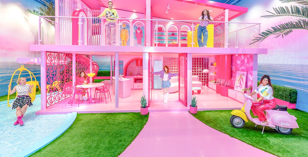 Barbie Dreamhouse experience with visitors exploring vibrant pink rooms and outdoor swing.
