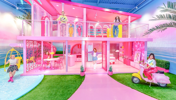 Barbie Dreamhouse experience with visitors exploring vibrant pink rooms and outdoor swing.