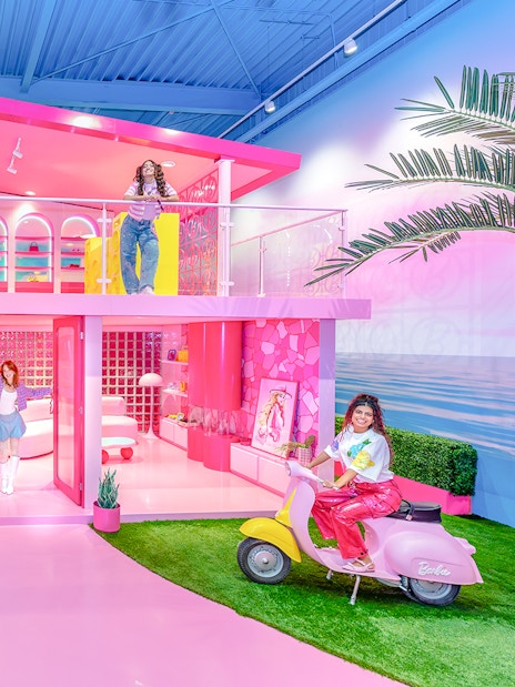 Barbie Dreamhouse experience with visitors exploring vibrant pink rooms and outdoor swing.