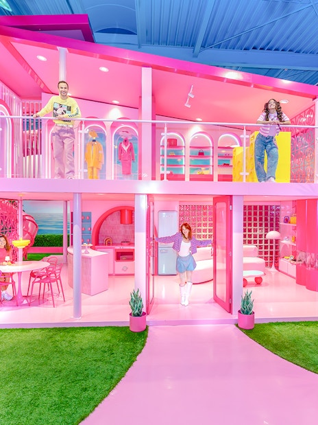 Barbie Dreamhouse experience with visitors exploring vibrant pink rooms and outdoor swing.