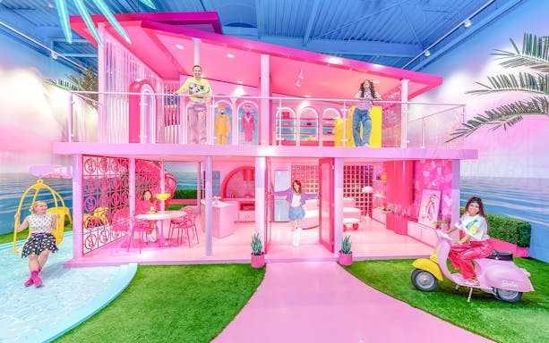 Barbie Dreamhouse experience with visitors exploring vibrant pink rooms and outdoor swing.