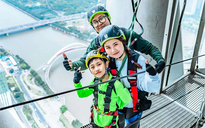 Family enjoying an adventure at Canton Tower, Guangzhou, with safety gear.