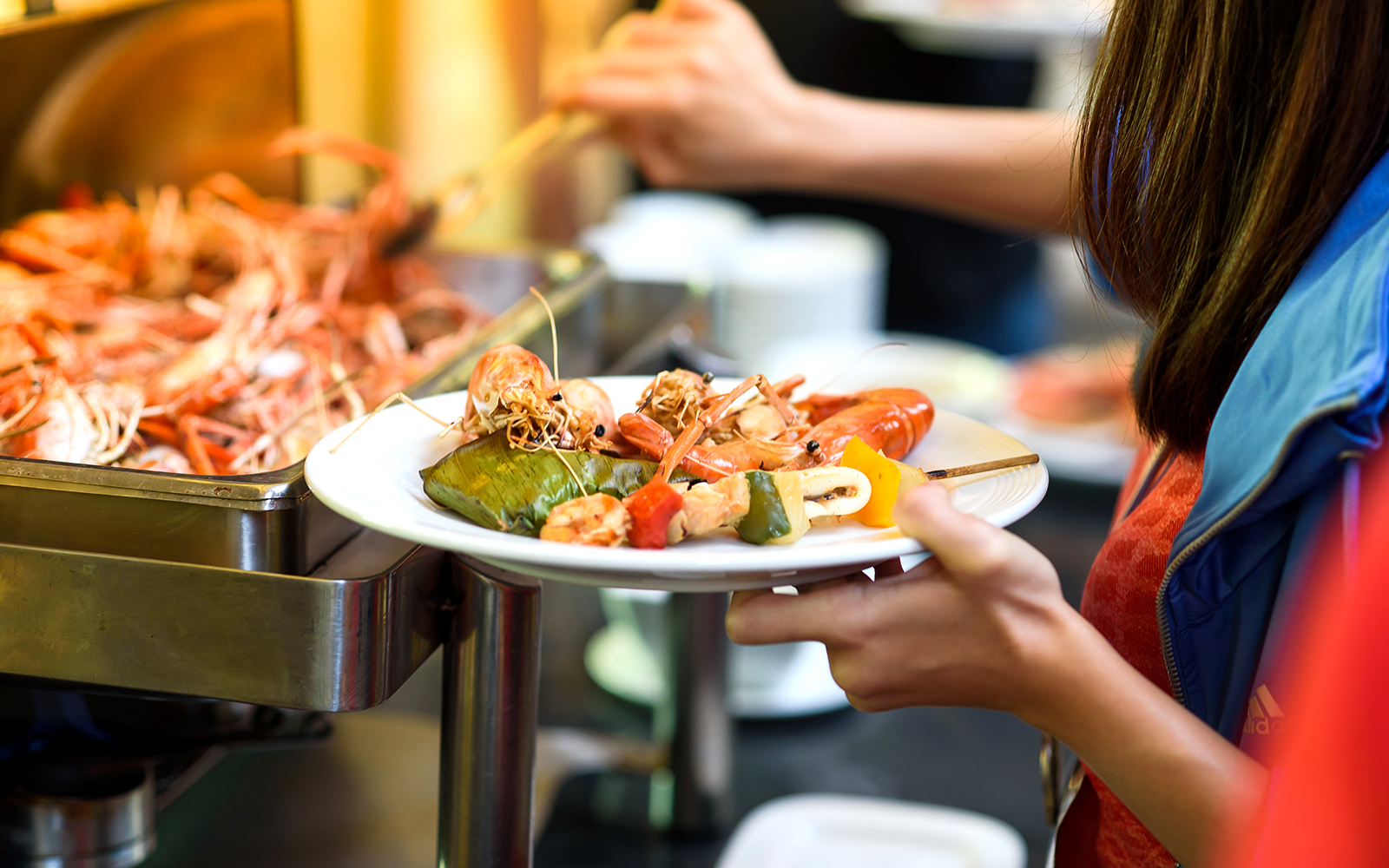 Seafood buffet selection with prawns and vegetables on a plate.