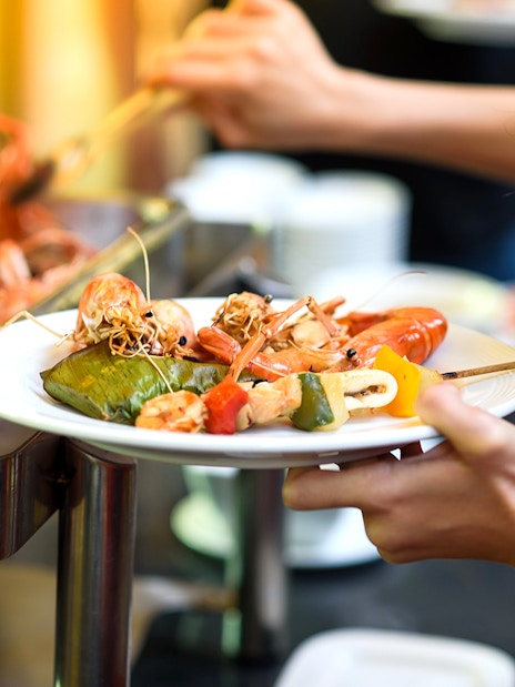 Seafood buffet selection with prawns and vegetables on a plate.