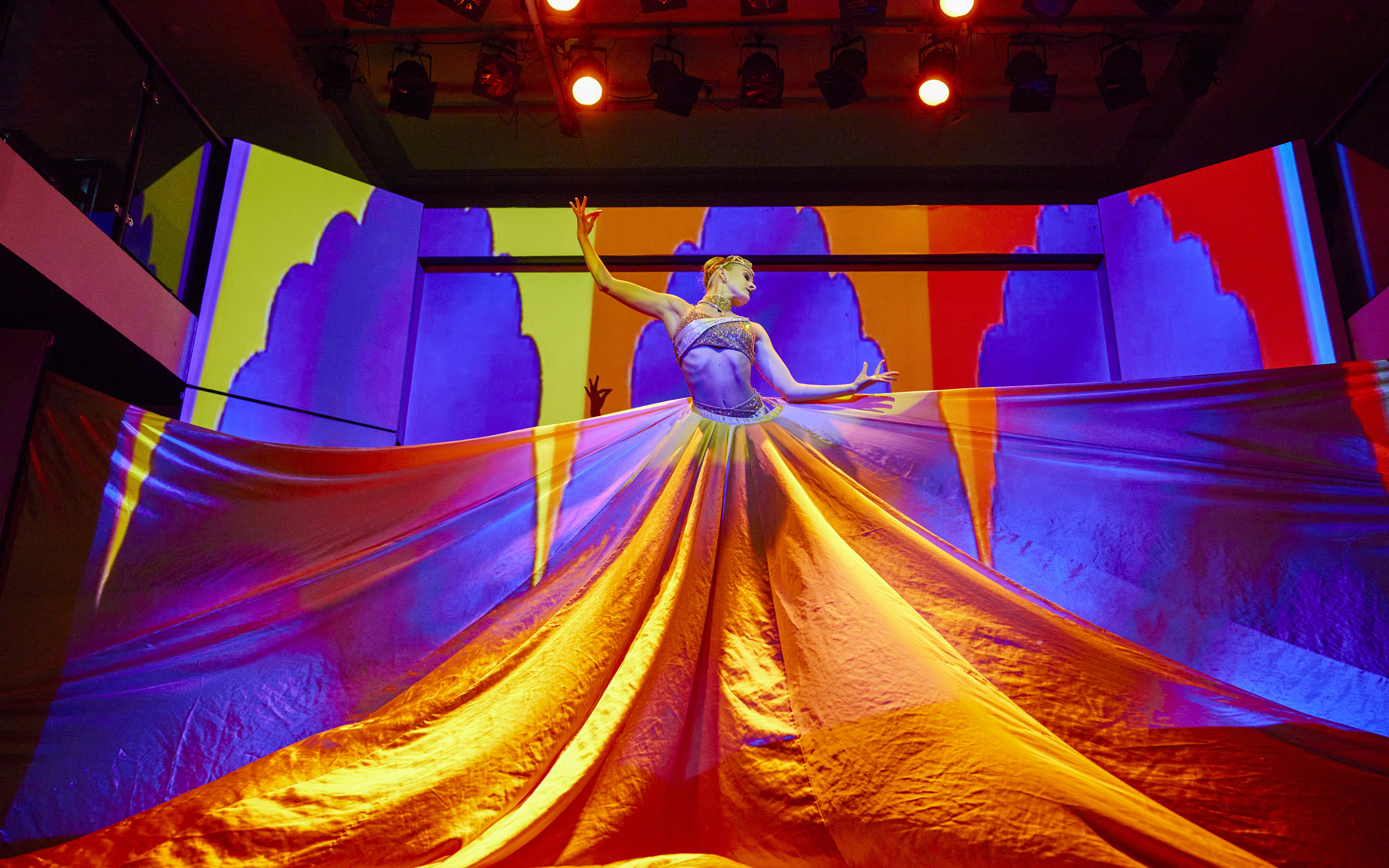 Performer on stage with colorful fabric backdrop during Showboat Vivid Sydney dinner cruise cabaret.