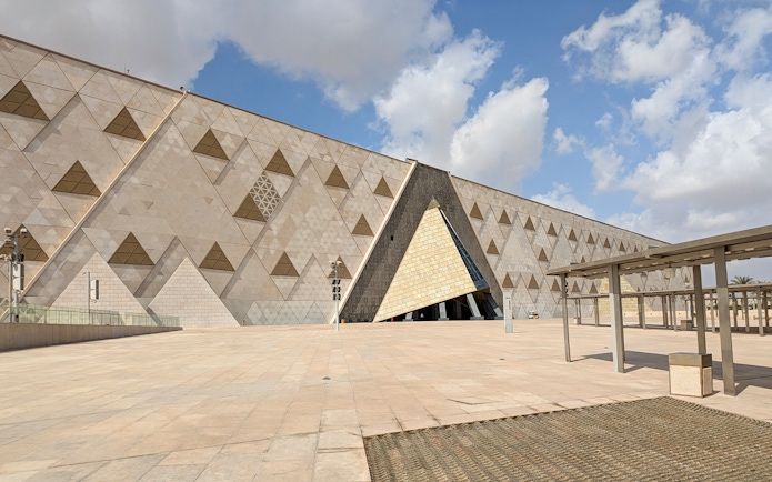 Grand Egyptian Museum facade with geometric patterns under a blue sky.