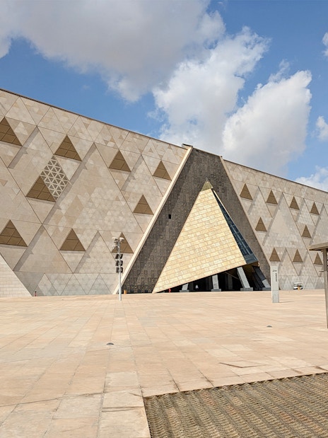 Grand Egyptian Museum facade with geometric patterns under a blue sky.
