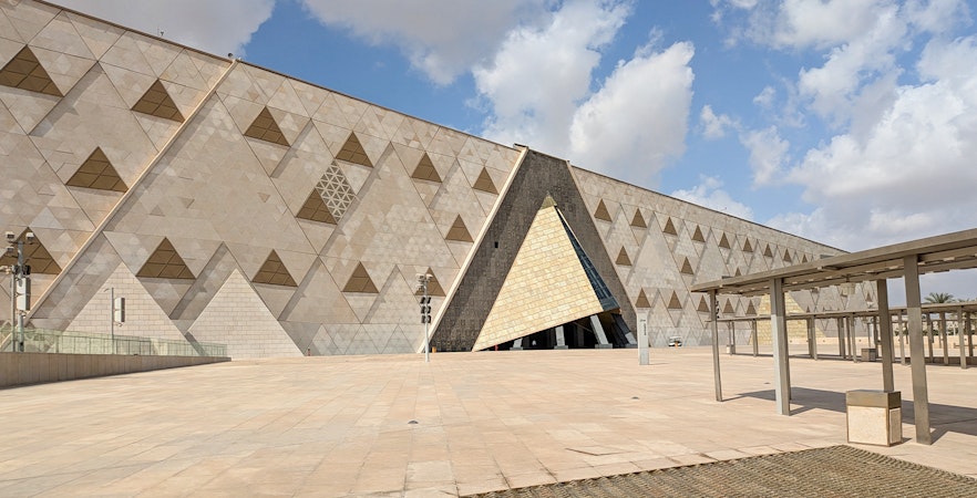 Grand Egyptian Museum facade with geometric patterns under a blue sky.