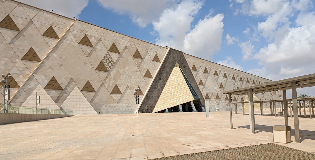 Grand Egyptian Museum facade with geometric patterns under a blue sky.