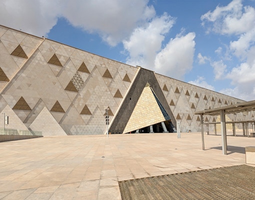 Grand Egyptian Museum facade with geometric patterns under a blue sky.