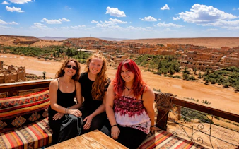 Scenic view of Aït Benhaddou village with three people seated in Marrakech, Morocco.