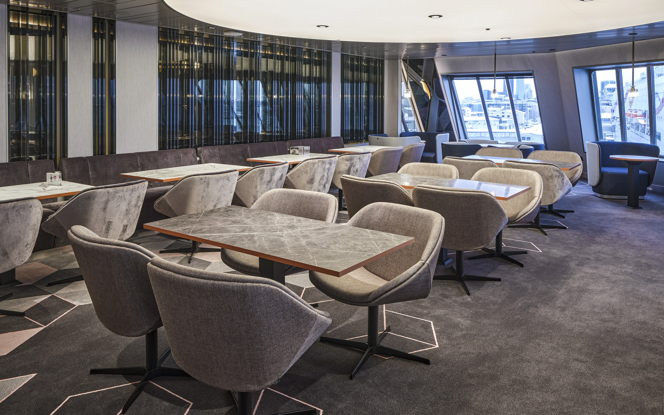 Modern seating area on a ferry from Helsinki to Tallinn with large windows.
