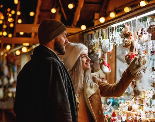 Couple exploring festive decorations at a holiday market stall.