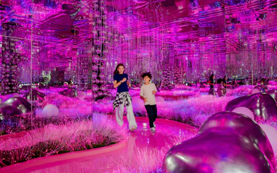 Visitors exploring vibrant pink mirrored room at House Of Hype exhibit.