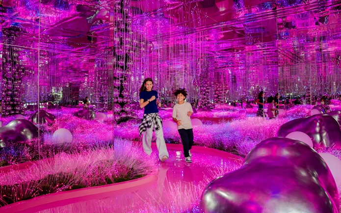 Visitors exploring vibrant pink mirrored room at House Of Hype exhibit.