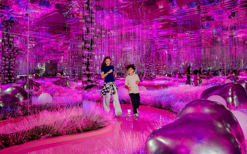 Visitors exploring vibrant pink mirrored room at House Of Hype exhibit.