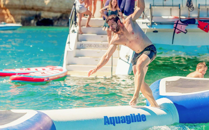 Tourist balancing on inflatable water toy near Ponta da Piedade, Lagos.