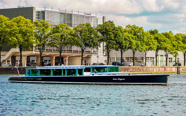 VIP Canal Cruise on Stan Huygens boat passing modern building in Amsterdam.