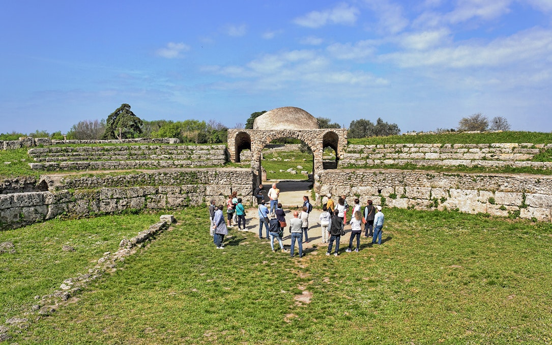 Visitors exploring ancient ruins at the Archaeological Park of Paestum, Italy.