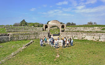 Visitors exploring ancient ruins at the Archaeological Park of Paestum, Italy.