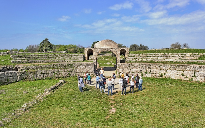 Visitors exploring ancient ruins at the Archaeological Park of Paestum, Italy.