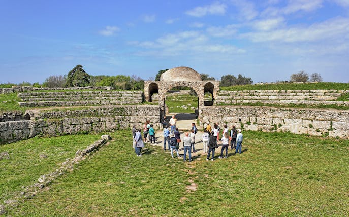 Visitors exploring ancient ruins at the Archaeological Park of Paestum, Italy.