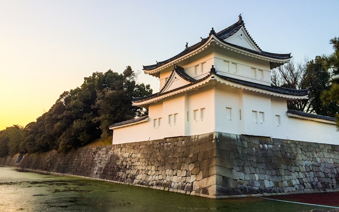 Nijo Castle in Kyoto with stone walls and traditional architecture at sunset.