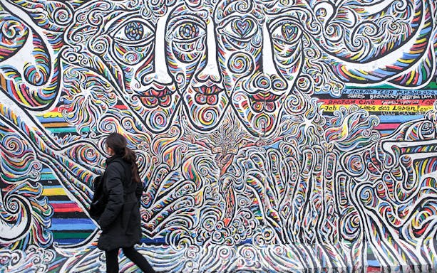 Woman viewing colorful mural at East Side Gallery, Kreuzberg, Berlin.