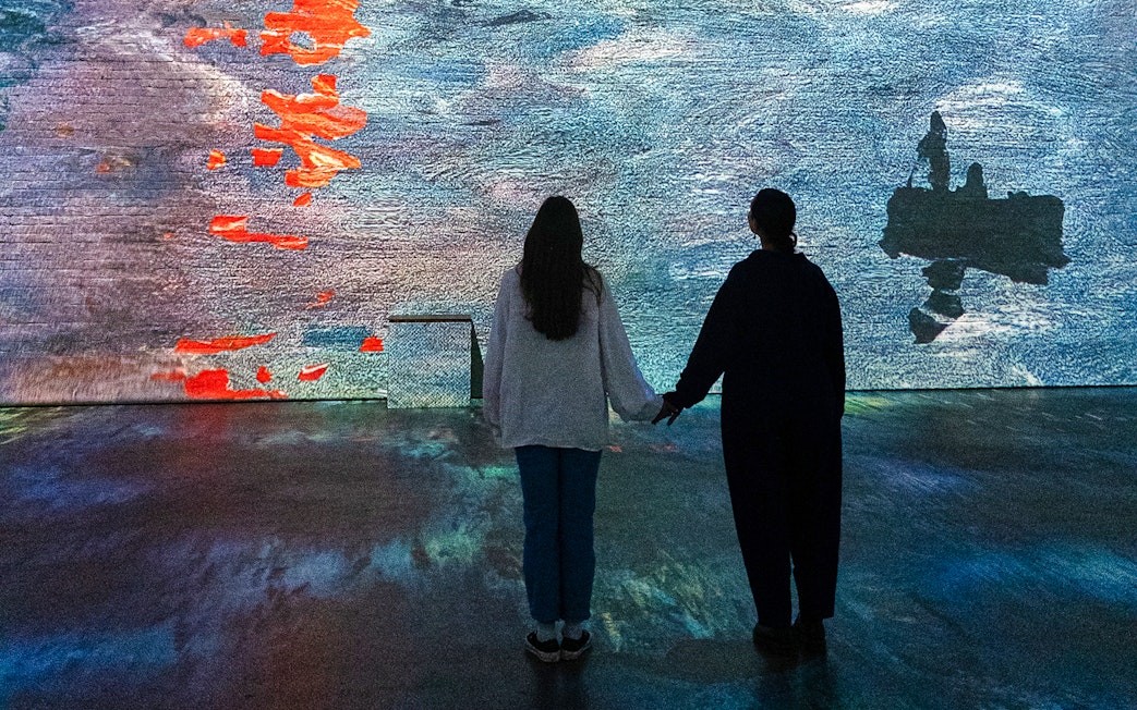 Visitors viewing Monet projections at Fabrique des Lumières exhibition.