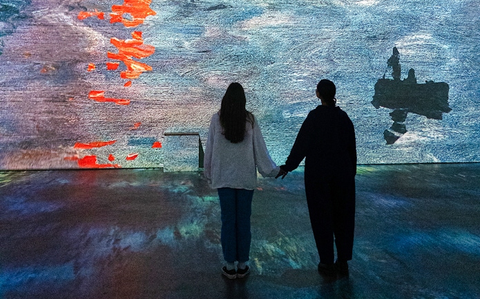 Visitors viewing Monet projections at Fabrique des Lumières exhibition.