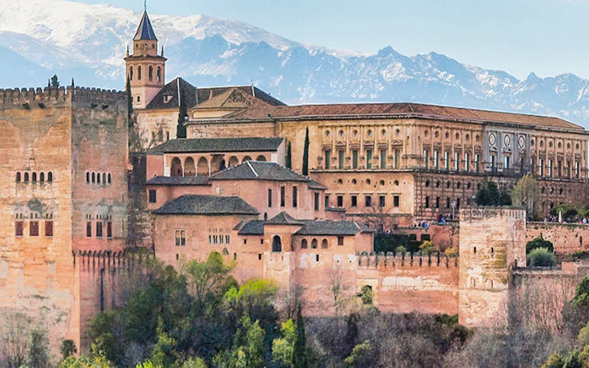 Alhambra palace complex in Granada with Sierra Nevada mountains in the background.