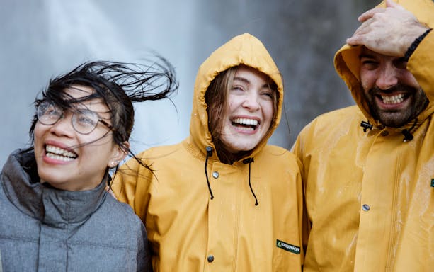 Tourists in raincoats smiling on a Milford Cruise day trip in New Zealand.