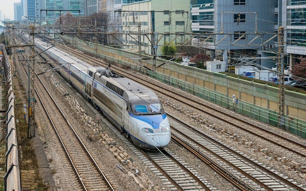 High-speed KTX train traveling on tracks in urban South Korea.