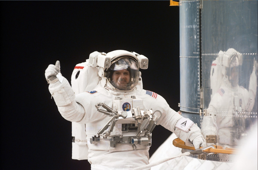 Astronaut Steve Smith in space suit with Earth in background.