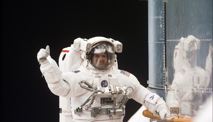 Astronaut Steve Smith in space suit with Earth in background.