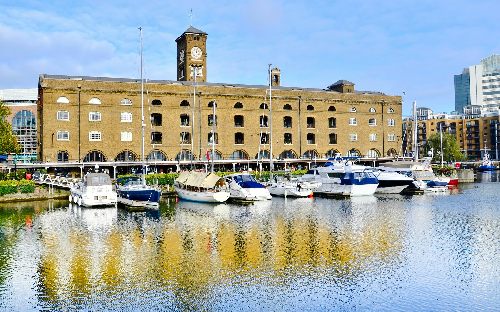 Boats moored at St Katharine Docks with historic warehouse in London.