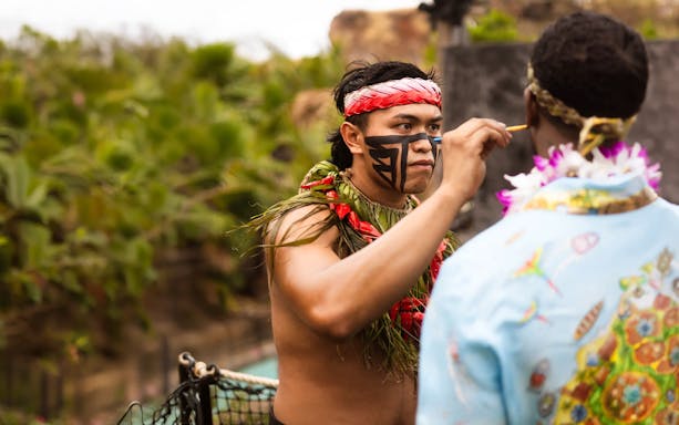 Performer applying face paint at Chief's Luau, Oahu, Hawaii.