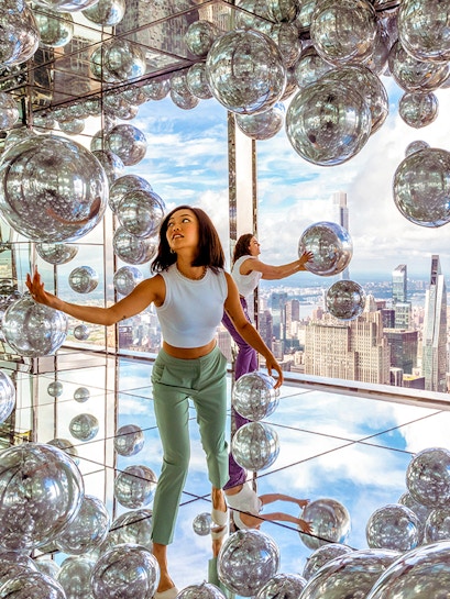 Visitors exploring mirrored room at Summit One Vanderbilt with New York City skyline views.