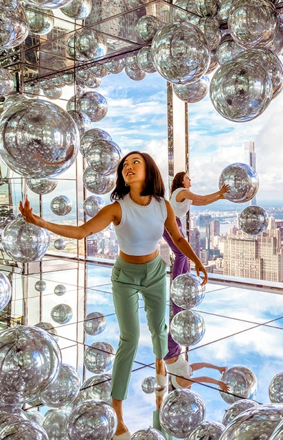 Visitors exploring mirrored room at Summit One Vanderbilt with New York City skyline views.