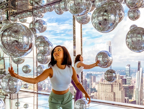 Visitors exploring mirrored room at Summit One Vanderbilt with New York City skyline views.