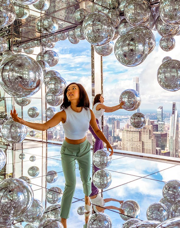 Visitors exploring mirrored room at Summit One Vanderbilt with New York City skyline views.