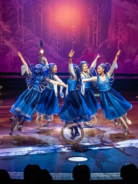 Performers in blue costumes on unicycles during a Las Vegas entertainment show.